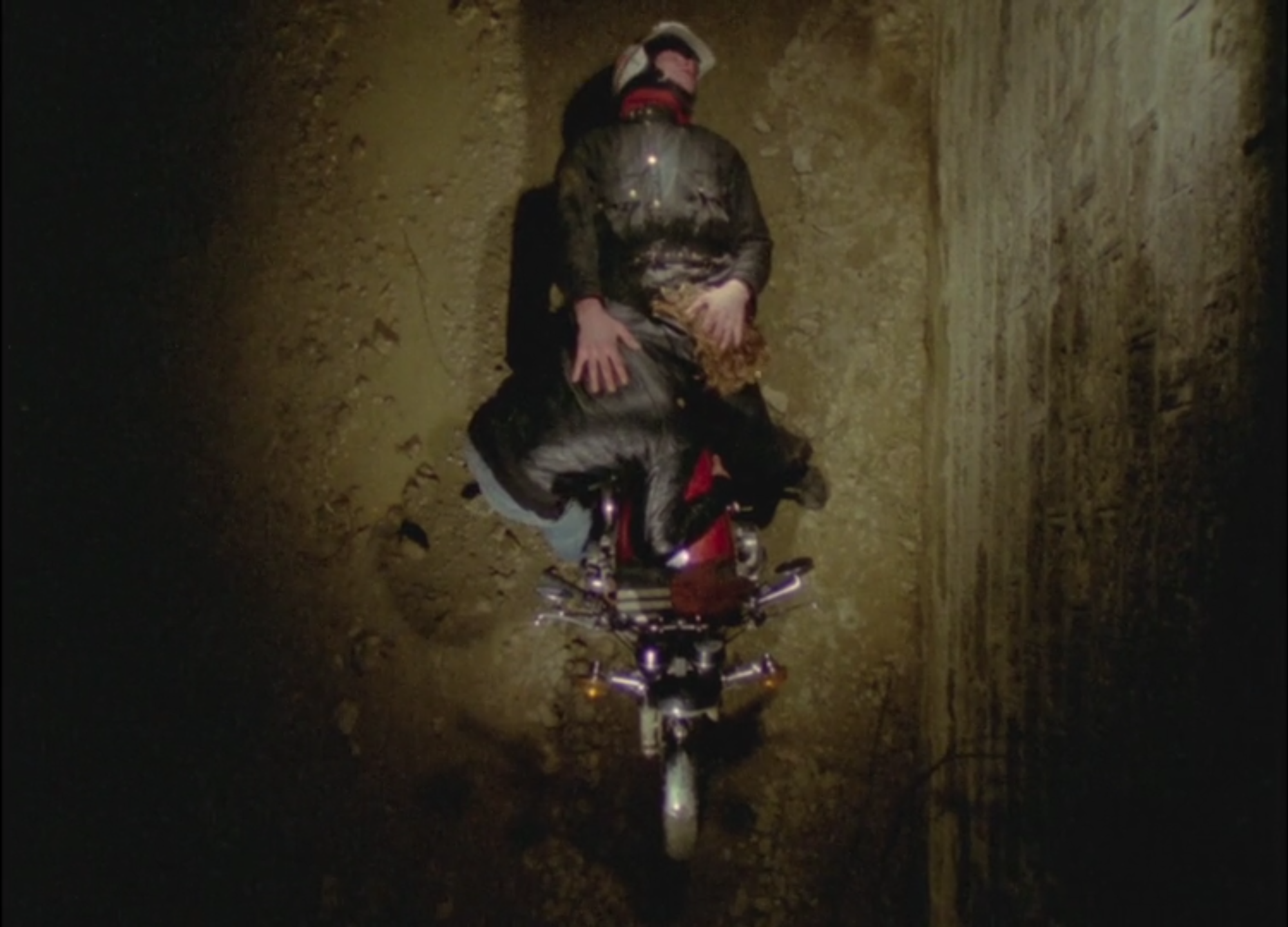 Another frame from Equation to an Unknown, from an aerial perspective we see one man giving another a blowjob splayed out over his motorcycle